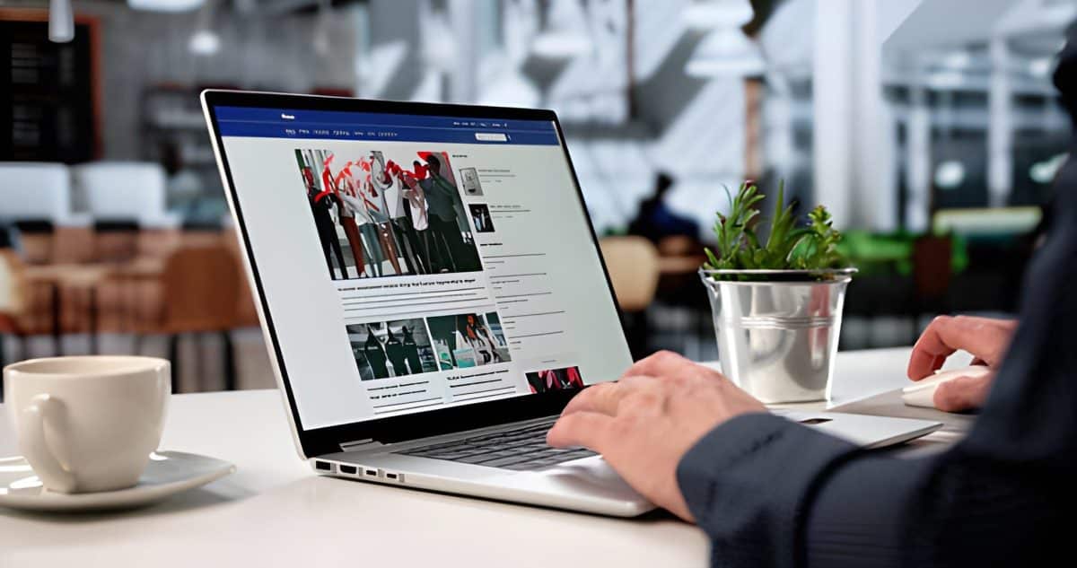 Junger Journalist tippt Artikel über Laptop im Café und schaut Nachrichten