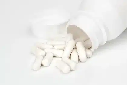 Apotheker berät einen Patienten an der Apothekentheke mit Medikamentenregalen im Hintergrund