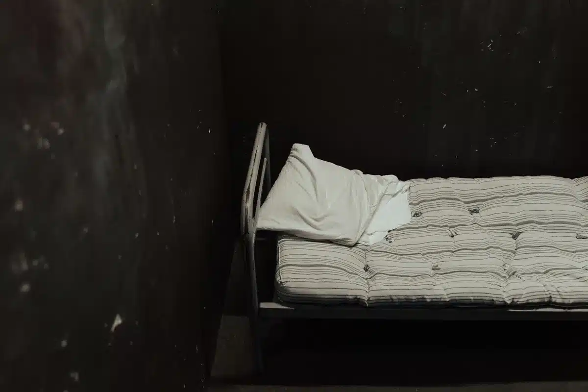 Ein dunkles, k&uuml;hles Schlafzimmer mit gemachtem Bett und geschlossenen Vorh&auml;ngen
