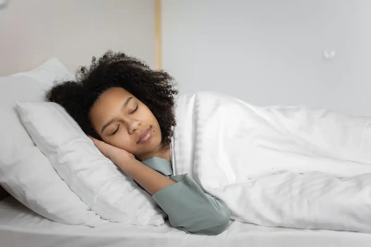 Person schl&auml;ft ruhig und erholsam in einem Bett