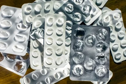 Melatonin-Tabletten neben Wasser und Notizbuch auf einem Nachttisch im Morgenlicht