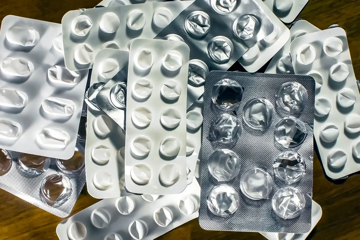 Melatonin-Tabletten neben Wasser und Notizbuch auf einem Nachttisch im Morgenlicht