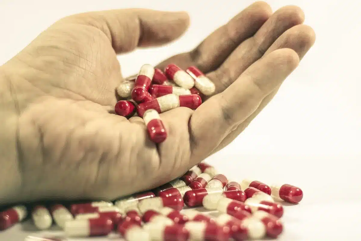 Apothekentresen bei Tageslicht mit Rezeptübergabe und unscharfen Medikamentenregalen im Hintergrund